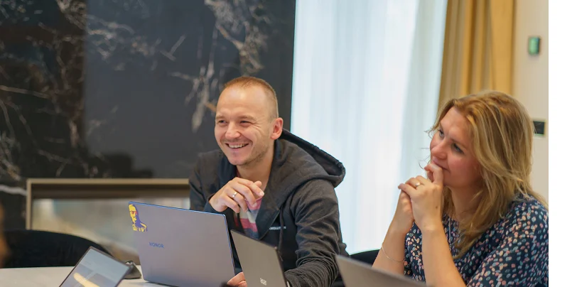 Zwei Teammitglieder der SEO Revolution besprechen ein Projekt und lachen gemeinsam.