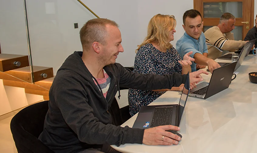 Teammitglieder arbeiten gemeinsam am Laptop während eines SEO-Meetings