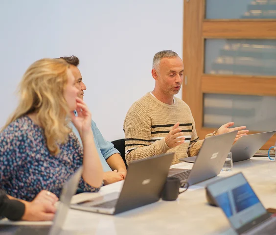 Drei Personen bei einer Teambesprechung mit Laptops am Konferenztisch