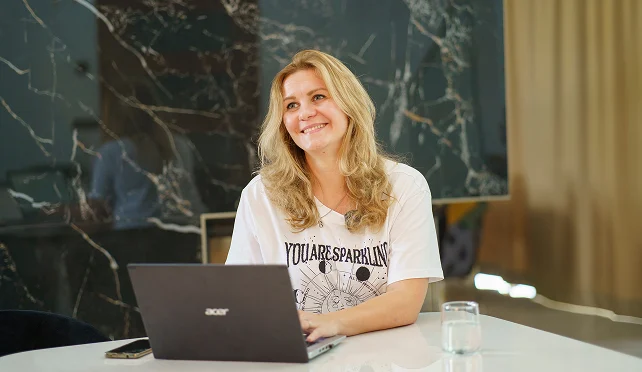 Valeria lächelt am Laptop während einer Beratungssituation im Büro